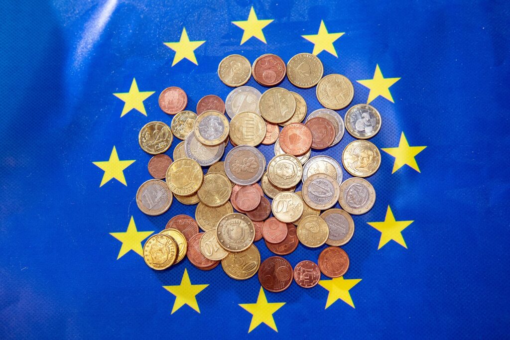Gestapelte Euromünzen auf einem Tisch, daneben liegen zusammengeheftete Papierbelege