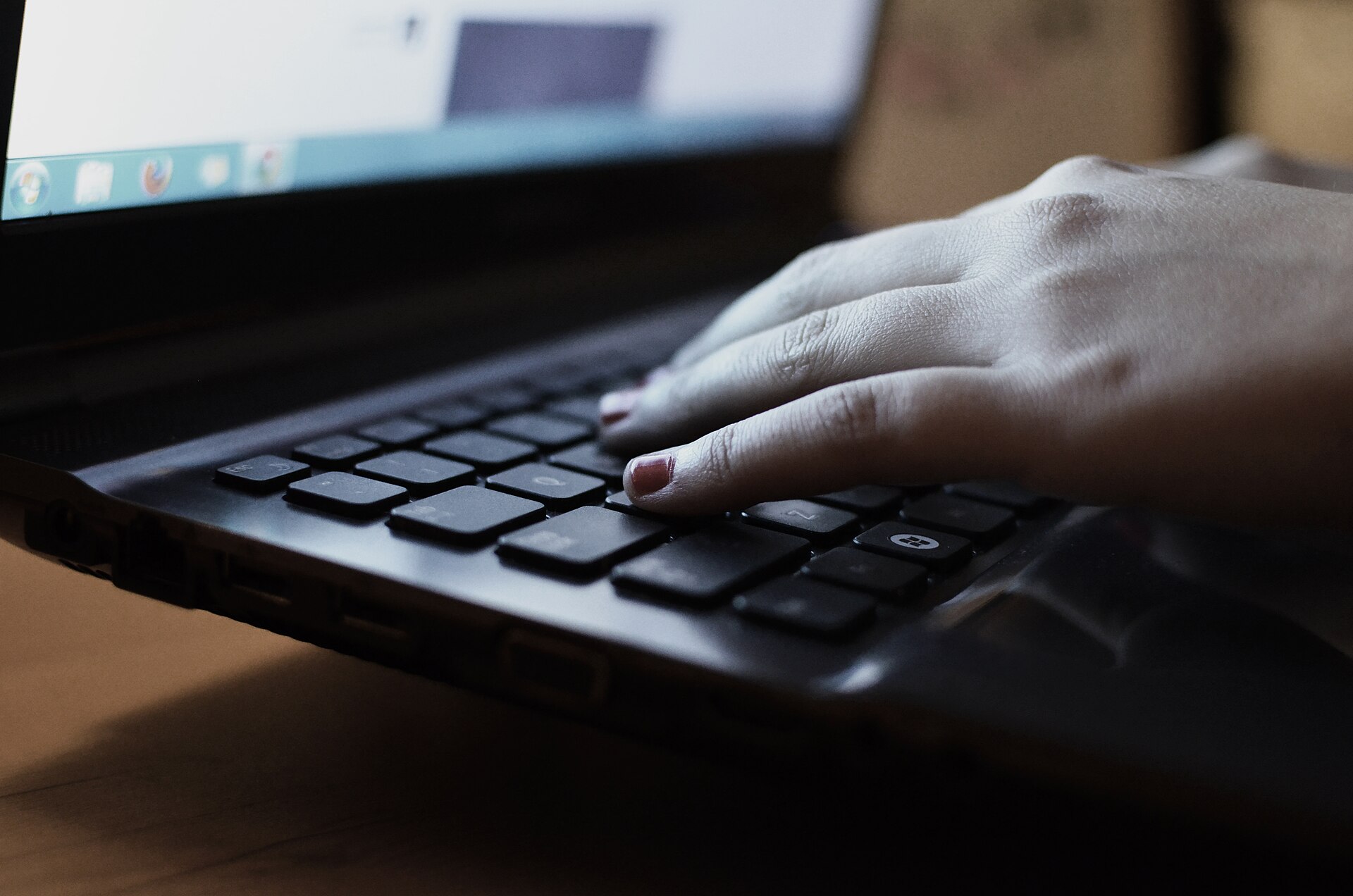 Kreditkarte liegt auf einer Laptoptastatur, daneben ein Smartphone mit geöffneter Bestellseite