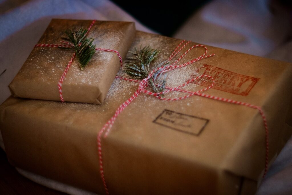 Geschenkpapier, Schere und Band liegen zum Einpacken auf einem Tisch bereit