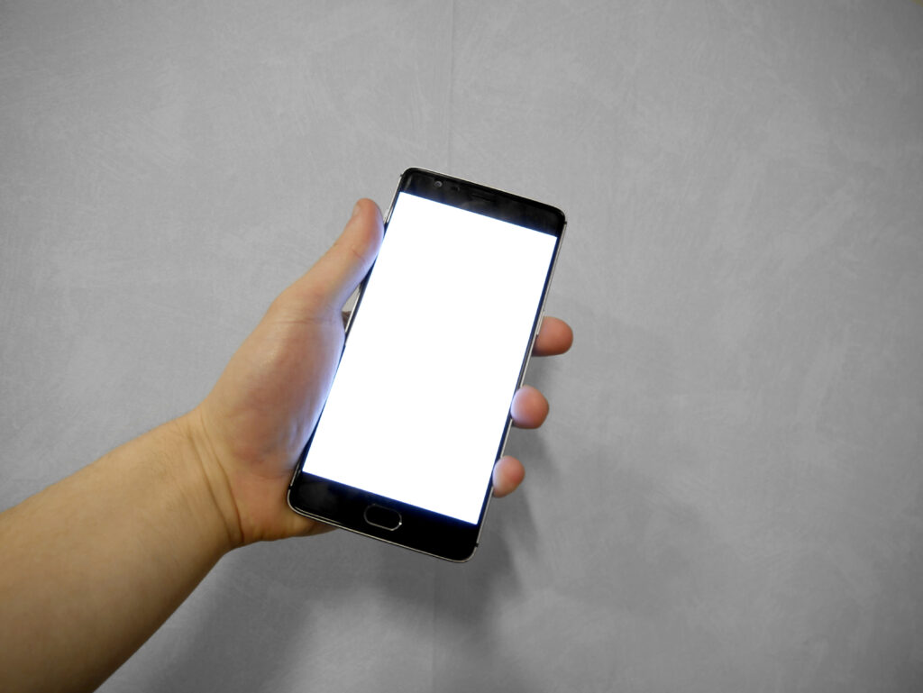 Hand h&auml;lt ein Smartphone, auf dem Bildschirm ist eine Produktseite mit Warenkorb-Button zu sehen