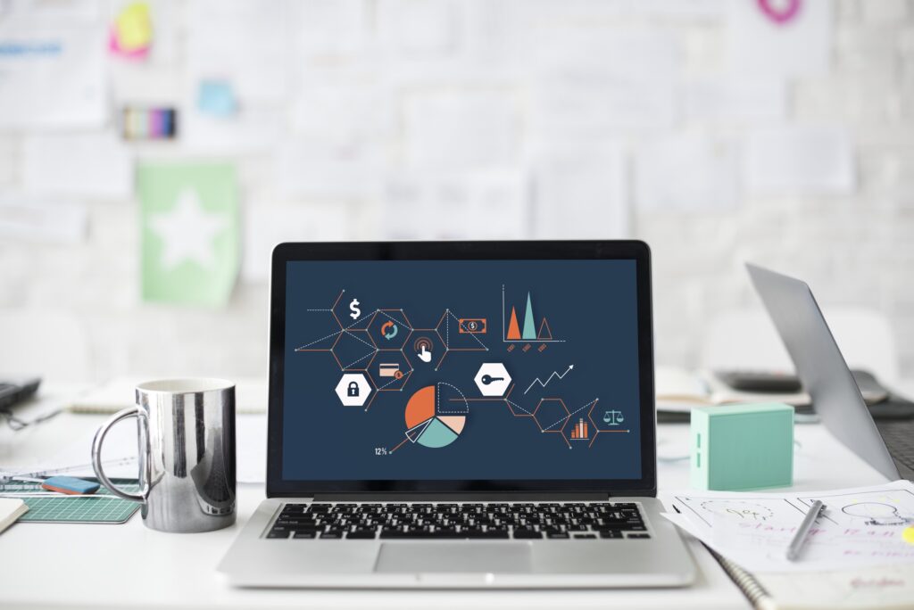 Laptop-Bildschirm zeigt ein Balkendiagramm mit mehreren farbigen Säulen auf einem Schreibtisch