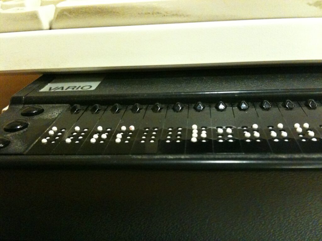 Braillezeile liegt vor einer Tastatur auf einem Schreibtisch in einem hellen B&uuml;ro